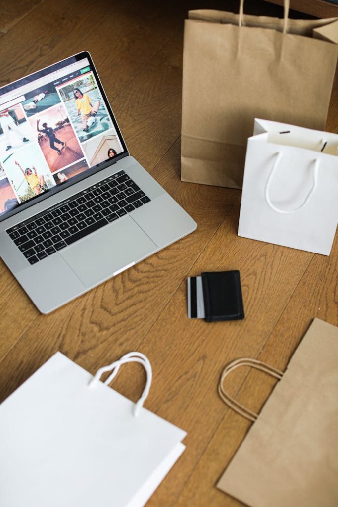 Mastering the First Impression: Your intriguing post title goes here Laptop with shopping bags and a credit card on a wooden floor, symbolizing online shopping.