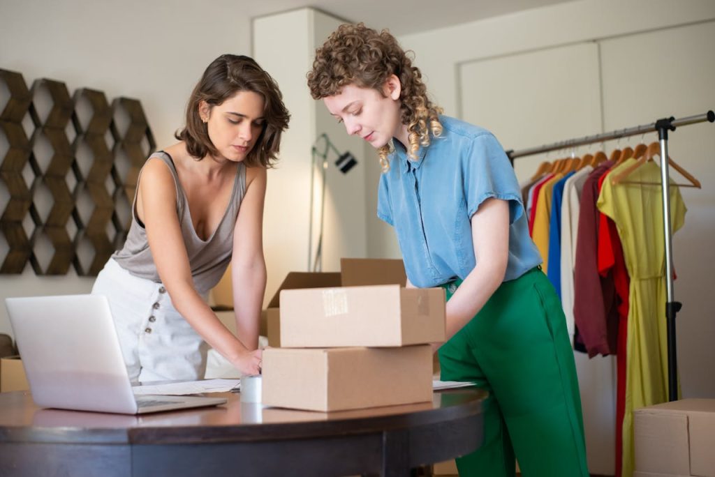 Two women packing boxes in a fashion boutique, working on an e-commerce project.